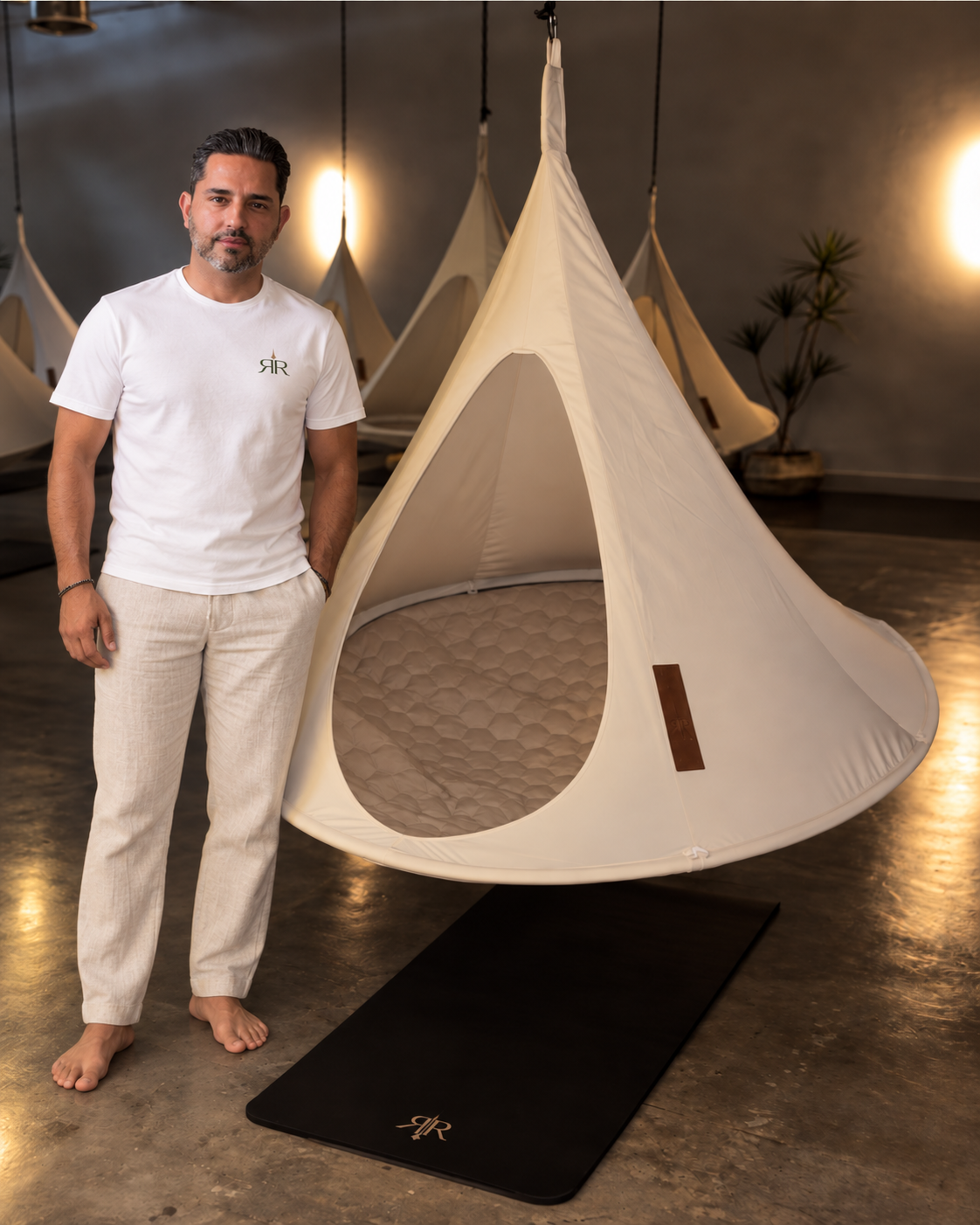 Kia Illulian, founder of Reset Room, standing beside a cocoon pod in the Reset Room studio
